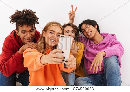 Group of cheerful teenagers isolated over white background, taking a selfie