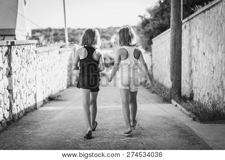 Identical Twin Girls Sisters Walking The Island Streets Of Croatia.