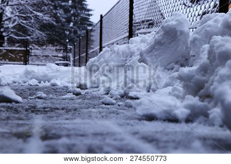 A Snow Pile Near Fence. Trying Shoveling Snow From Driveway. Twenty Centimetres Snow Coverlet Must B