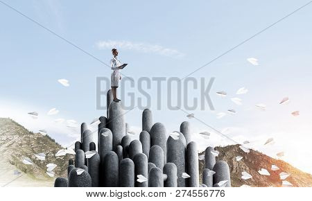 Young Female Doctor With Folder In Hands Satnding On Stone Column