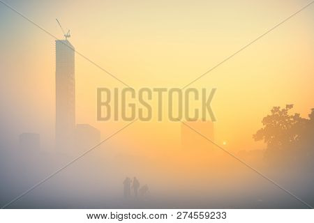 Sunrise At Kolkata Maidan In A Foggy Winter Morning. Sunrises At The Horizon Above City Skyscappers 