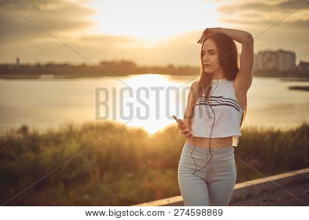 Young Beautiful Caucasian Girl Listening To Music With Smartphone Walking In The City With Headphone