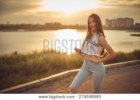 Young Beautiful Caucasian Girl Listening To Music With Smartphone Walking In The City With Headphone