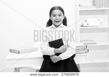 Happy To Enter Into First Form. Girl Child Holds Book Stand Near Table White Background. Schoolgirl 