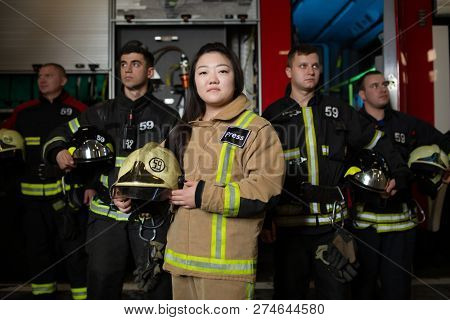 Photo of four young male and female firefighters on background of fire truck