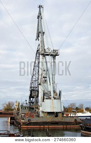 Old Shabby And Rusty Port Crane In The Harbor.