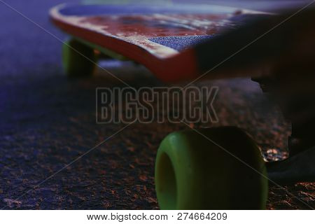 A Closeup Of A Red And Black Skateboard With Bluish-black Street Underneath