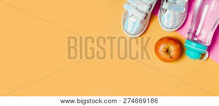 Child Sneakers And Bottle Of Water On Orange Background.