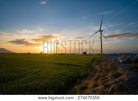 Wind Turbines Farm And Agricultural Fields On Blue Sky. Turbine Green Energy Electricity Or Wind Tur