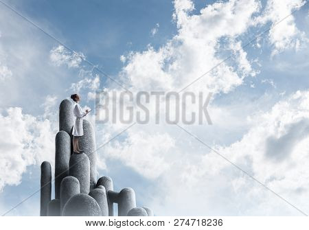 Young Female Doctor With Folder In Hands Satnding On Stone Column