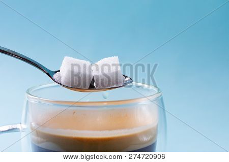 Two Cubes Of Sugar In Spoon Over Cup Of Coffee
