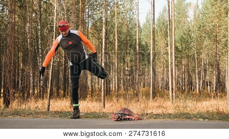 Training An Athlete On The Roller Skaters. Biathlon Ride On The Roller Skis With Ski Poles, In The H
