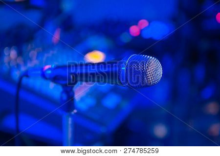 Microphone On The Blurred Background Of The Audio Mixer Of The Musician.