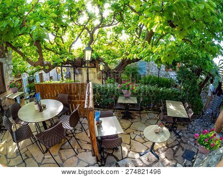 Traditional Restaurant Terrace Inside Eze Village With Tables And Chairs Among Vintage House Archite