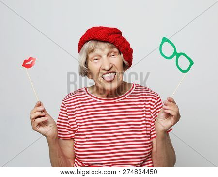 funny grandmother wearing red clothes holding falce glasses and ready for party