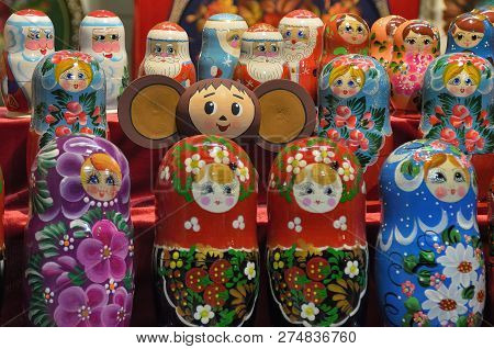 Cheburashka On The Background Of Nesting Dolls And Figures Of Santa Claus In The Background