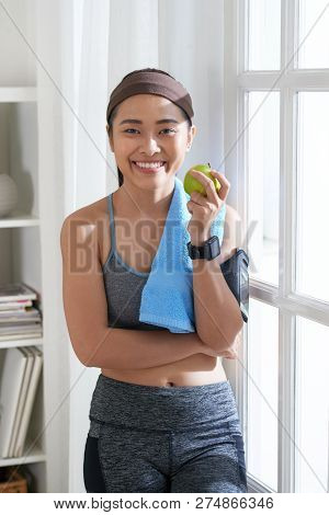 Portrait Of Pretty Smiling Sporty Vietnamse Woman Snaking With Green Juicy Apple