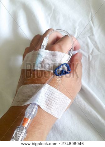 Patient Hand With The Tube Of Normal Saline Infusion On White Cloth Background