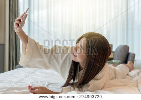 Asian Woman In Bathrope Suit Using The Smart Mobile Phone With Smiling Action To Selfie Herself On T