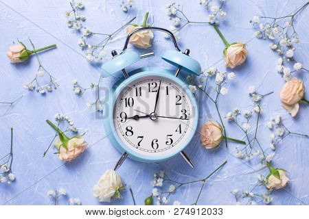 Blue Alarm Clock And Pattern From Fresh White Gypsofila And Rose  Flowers On Blue Textured Backgroun