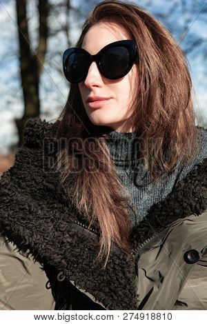 Attractive young woman wearing gray dress and hakki jacket with long fair hair posing outdoor in autunm or spring park over nature outdoor. Beautiful caucasian model portrait.