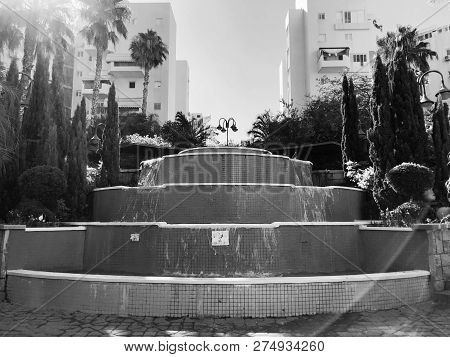 Residential Buildings And Fountain Surrounded With Green Plants In  Rishon Le Zion.