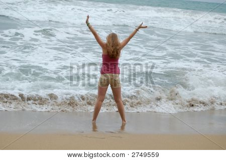 Donna sulla spiaggia con le braccia alzate