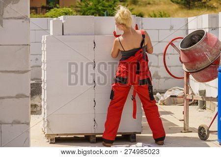 Strong Woman Working On Construction Site, Building House, Installing Gray Airbricks. Industrial Wor