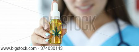 Close-up Of Female Hand Holding Bottle With Cannabinoid Oil And Marijuana Green Leaf Sign. Smiling D