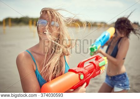 Crazy happy woman attacked her frinds girl with water gun at beach at vacation.