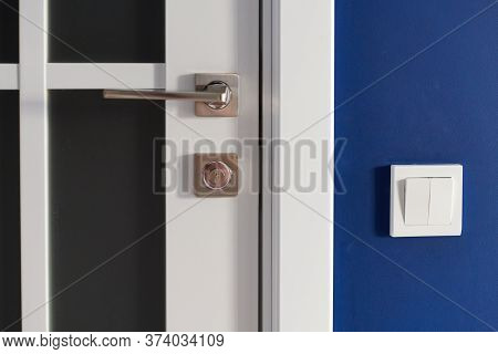 White Interior Door With Handle. Blue Wall In Modern Apartment, Light Switch Nearby. Wooden Closed D