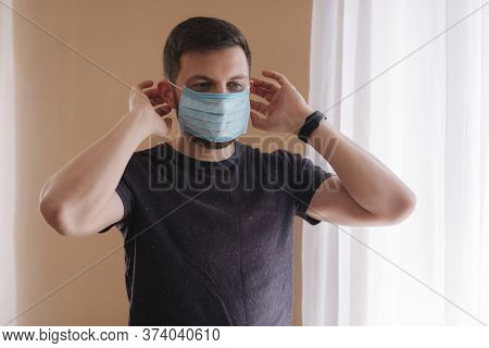 Man Put On Madical Mask At Home. Young Man In Protective Mask. Coronavirus Theme