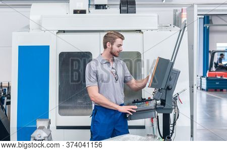 Worker operating computer-controlled machine tool on the screen