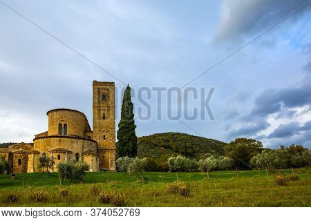 Ancient medieval magnificent abbey of San Antimo. Tall slender cypress adorns the meadow around the abbey. Picturesque Tuscany. The concept of active, rural and photo tourism