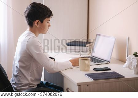 Schoolboy Study At Desk In His Room. Boy Use Laptop For Lessons. Drink Tea. Books And Tablet On The 