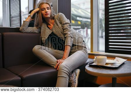 Girl In Grey Suit Posing In Cafe With Cup Of Black Coffee