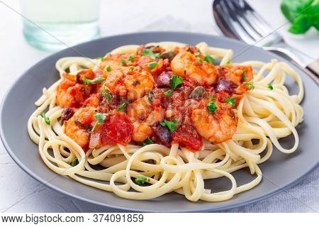 Linguine Puttanesca Pasta With Shrimps In Spicy Tomato Basil Sauce Garnished With Parsley, On A Gray