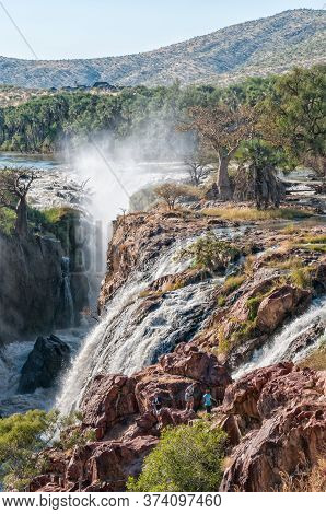 Epupa, Namibia - May 24, 2011: Part Of The Epupa Waterfalls In The Kunene River. People, Baobab And 
