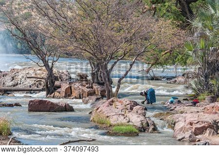 Epupa, Namibia - May 24, 2011: A Woman Washing Clothes In The Kunene River At The Top Of The Epupa W