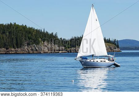 A Light Blue Sailboat Is Sailing Peacefully In Frenchman Bay Around The Porcupine Islands In Bar Har