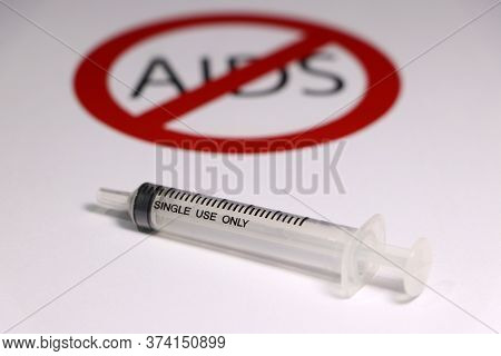 A Syringe On White Floor With Out Focus Symbolic Of Anti Aids.