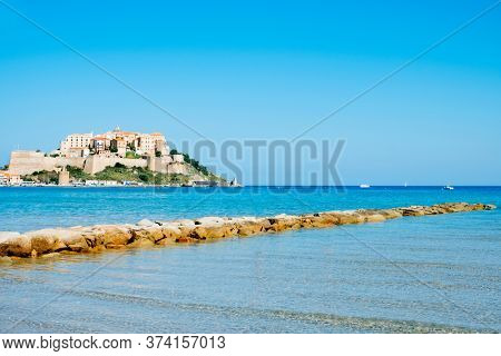 a view of Calvi, in Corsica, France, with its famous citadel on the rigth on the top of a promontory, and the Mediterranean sea in the foreground