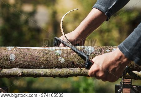A Man Is Shaving An Wooden Log With An Drawknife