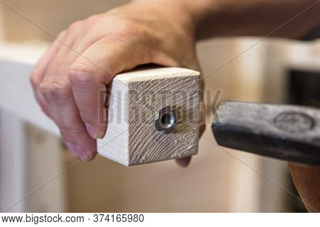 Man Is Installing A Adjustable Variable Screw In A Wooden Desk Or Table Leg