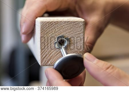 Man Is Installing A Adjustable Variable Screw In A Wooden Desk Or Table Leg