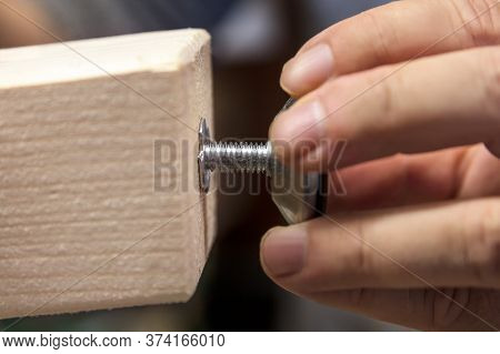 Man Is Installing A Adjustable Variable Screw In A Wooden Desk Or Table Leg