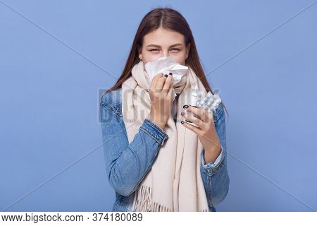 Young Caucasian Woman Has Runny And Common Cold, Holding In Hands Pills And Nasal Spray, Wearing War