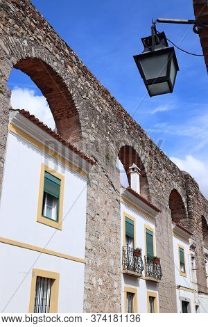 Evora Town In Portugal. Unesco World Heritage Site. Prata Aqueduct With Homes Beneath Arches.