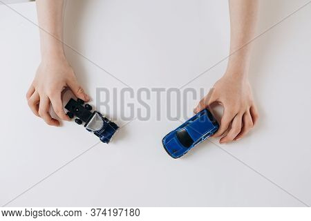 Two Toy Cars In Childrens Hands On A White Background. High Quality Photo