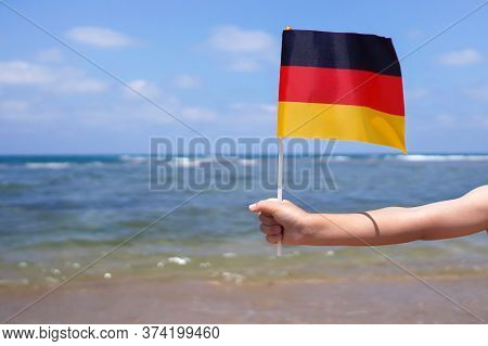Hands Of Kid Girl Holding Germany Flag Against The Sea Horizon. 3th Of October Independence Day Of G